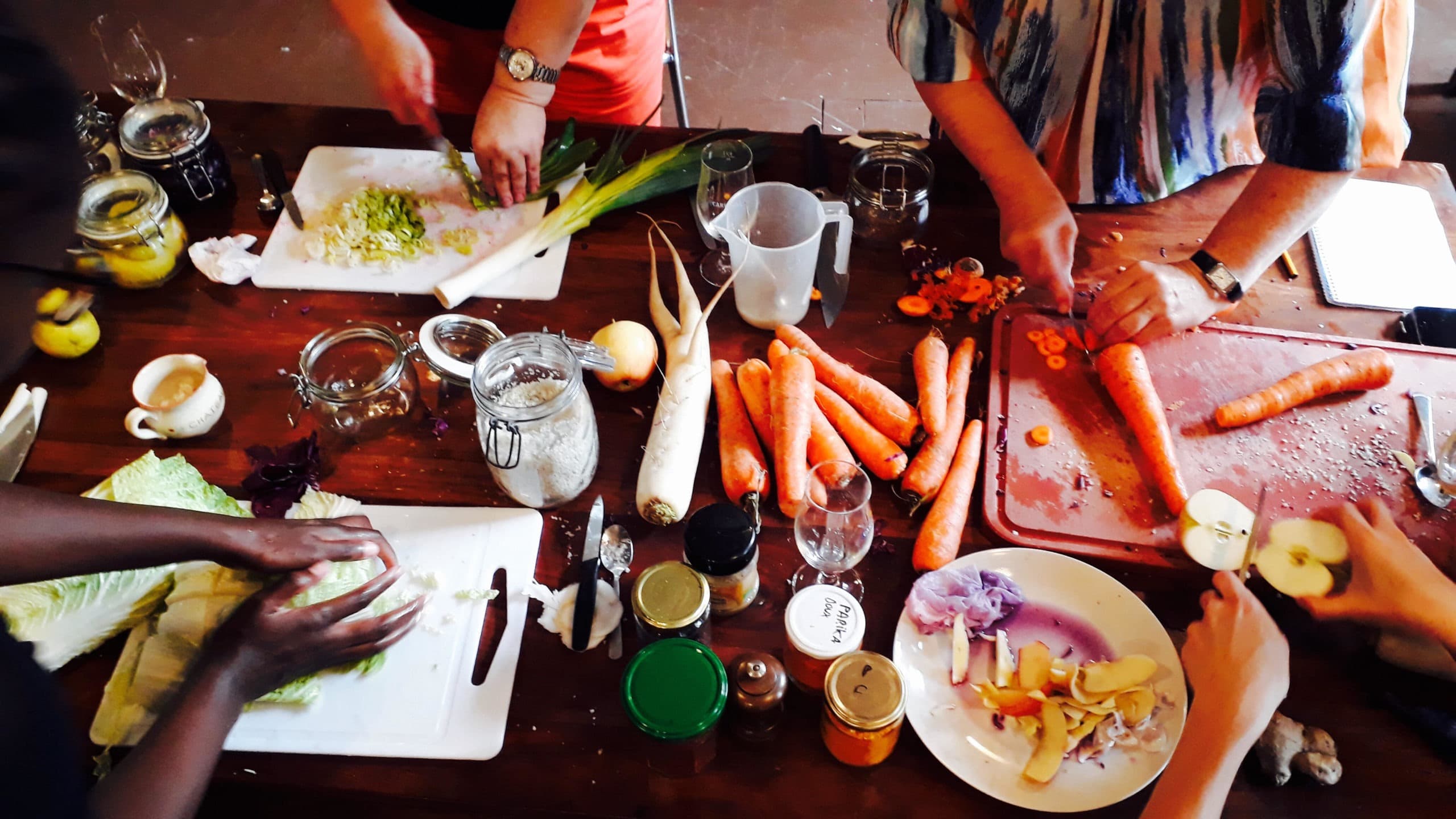 Vue plongeante d'un atelier de lacto-fermentation: mains, légumes, bocaux